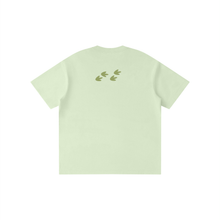 Load image into Gallery viewer, A light mint green short-sleeve t-shirt shown from the back, featuring a small graphic of four olive green leaf-like shapes arranged in a row near the upper back.